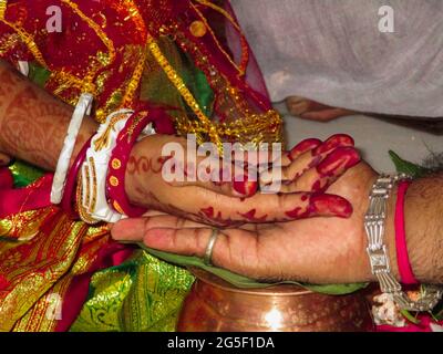 Eine Nahaufnahme der Hand einer gemalten Frau auf der Hand eines Mannes bei einer indischen hinduistischen Hochzeitszeremonie Stockfoto