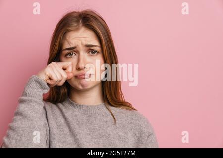 Junge Ingwer verärgert Frau weinen und wischen ihre Tränen isoliert über rosa Hintergrund Stockfoto