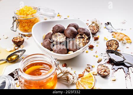 Nahaufnahme handgefertigter Süßigkeiten mit Honig, Rosinen, kandierten Orangenfrüchten und Erdnüssen in Schokolade. Süßigkeiten aus natürlichen Bio-Zutaten Stockfoto