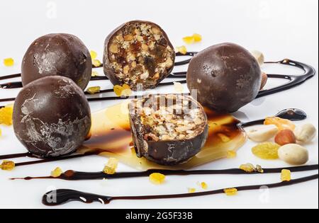 Stillleben handgemachte Süßigkeiten mit Honig, Rosinen, kandierten Orangenfrüchten und Erdnüssen in Milchschokolade. Süßigkeiten aus natürlichen und biologischen Zutaten. Stockfoto