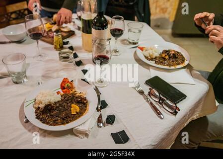 Typisch brasilianisches Gericht namens Feijoada. Hergestellt aus schwarzen Bohnen, Schweinefleisch und Wurst. Serviert auf einem weißen Teller während eines Meetings. Stockfoto