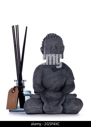 Graue Keramik Buddha Statue, Standign neben Glas Hause Parfüm Flasche mit Holzstäbchen. Isoliert auf weißem Hintergrund. Stockfoto