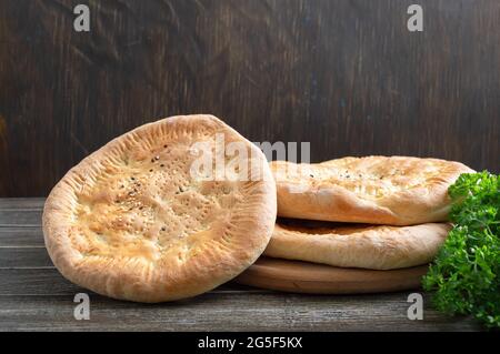 Traditionelles asiatisches einfaches Brot. Frisch gebackenes Fladenbrot mit Sesam auf rustikalem Holzhintergrund. Stockfoto
