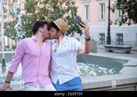 Gay Tourist paar küssen und nehmen ein Selfie am Brunnen auf einem Stadtplatz. Stockfoto