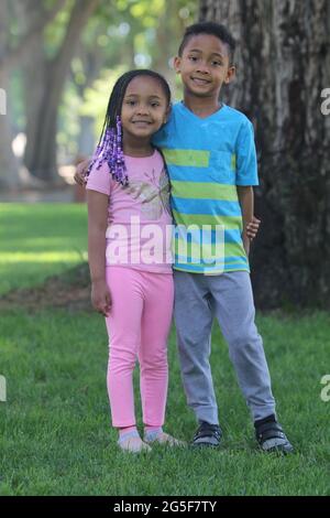 Ein flacher Fokus von zwei afroamerikanischen Kindern, die sich mit einem riesigen Lächeln im Gesicht halten Stockfoto