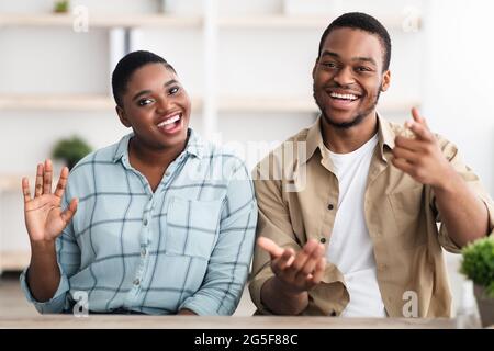 Hallo. Glückliches Afroamerikanisches Familienpaar Winkt Hand Lächelnd Zur Kamera Kommunikation Online Per Videoanruf Sitzen Im Haus. Porträt des zufriedenen C Stockfoto