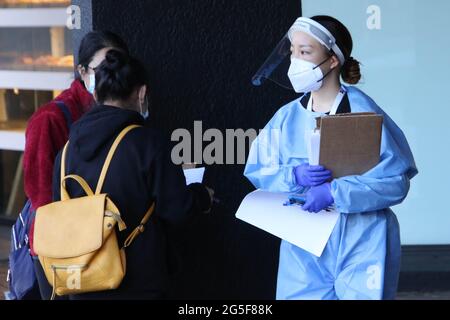 Sydney, Australien. Juni 2021. Nach einem Ausbruch des Covid-19 (Coronavirus) gelten die Bestellungen für den Aufenthalt zu Hause für den Großraum Sydney. Die zweiwöchige Sperrung mit „Stay-at-Home“-Bestellungen dauert bis Mitternacht, Freitag, den 9. Juli. Im Bild: Eine Frau mit PSA überprüft Personen, bevor sie ein Gebäude betreten. Kredit: Richard Milnes/Alamy Live Nachrichten Stockfoto