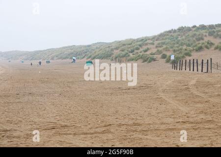 Camber, East Sussex, Großbritannien. 27 Juni 2021. Wetter in Großbritannien: Das später erwartete Regenwetter ist früh an den Sandstränden von Camber Sands in East Sussex angekommen. Einige Familien wollen den Tag genießen, wenn sie mit Regenschirmen und Regenponchos ankommen. Leerer Camber Sands Strand. Foto-Kredit: Paul Lawrenson /Alamy Live Nachrichten Stockfoto