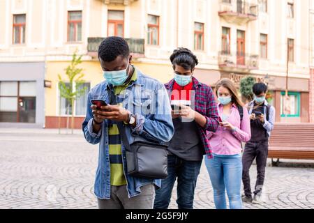 Menschen in Masken stehen Schlange, um soziale Distanz zu bewahren Stockfoto