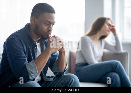 Familienprobleme. Porträt Eines Verärgerten Interrassischen Paares Auf Der Couch Sitzen Nach Streit, Deprimiert Junge Multikulturelle Ehepartner Leiden Beziehung Cri Stockfoto