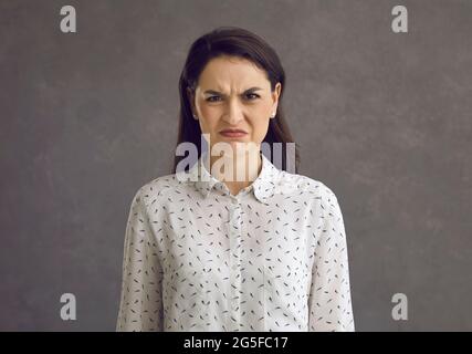 Porträt einer emotionalen jungen Frau mit runzelndem Grimasse, die ihren Ekel und ihre Abneigung zum Ausdruck bringt. Stockfoto