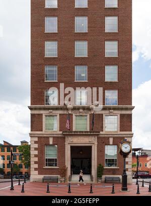 GREENVILLE, SC, USA-23. JUNI 2021: Das historische Gebäude der Handelskammer, errichtet 1924. Eine Frau kommt vorbei. Uhr. Stockfoto