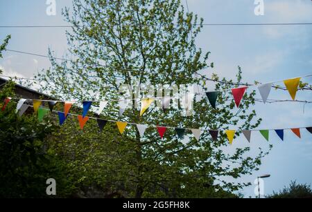 Ein Blick auf bunte dekorative Dreiecksflaggen für die Feier im Freien vor einem blauen Himmel Hintergrund Stockfoto