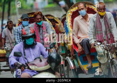 Ricksha-walas, oder Rikscha-Fahrer mit ihren Passagieren auf den Straßen von Dhaka. Die Bewohner der Hauptstadt Dhaka in Bangladesch stellen sich der Bedrohung durch den Corona-Virus COVID 19. Stockfoto