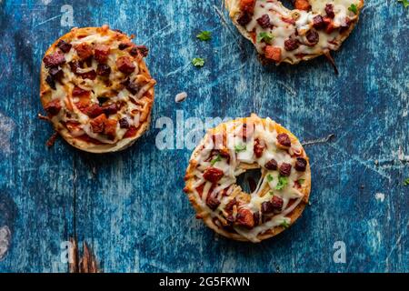 Oben unten Nahaufnahme von drei hausgemachten Pizza Bagels gegen. Ein blauer Hintergrund. Stockfoto