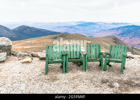 Reihe leerer Holzstühle auf der Spitze eines Berges an einem bewölkten Herbsttag. Wunderschöne Berglandschaft im Hintergrund. Stockfoto