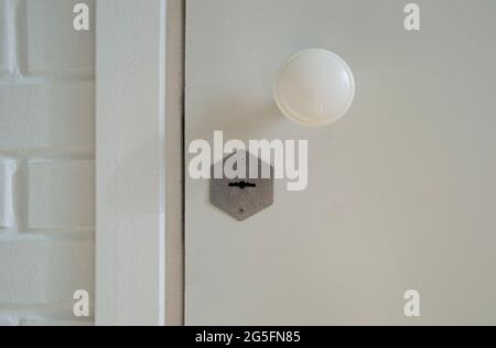 Geschlossene weiße Holztür mit Schloss und Griff. Stockfoto