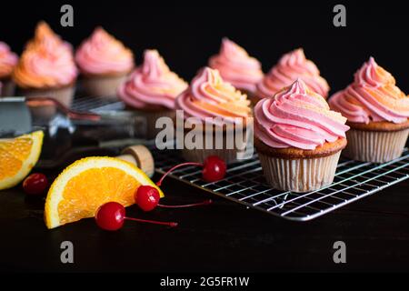 Tequila Sunrise Cupcakes on Wire Cooling Racks: Gebäck in Tequila-, Orange- und Kirscharomen Stockfoto