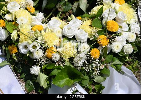 Kranz aus weißen und gelben Blumen auf einem Grab Stockfoto