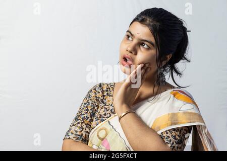 Isoliert auf weißem Hintergrund überrascht ein indisches Weibchen in Saree und schaut zu ihr rechts auf weißem Hintergrund Stockfoto