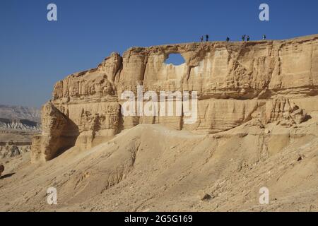Riesiger Sandsteinfelsen in der Negev-Wüste genannt Mount Rechev mit Blick auf das trockene Flussbett von Nachal Zin, links, wird das Loch in der Mitte das Auge genannt Stockfoto