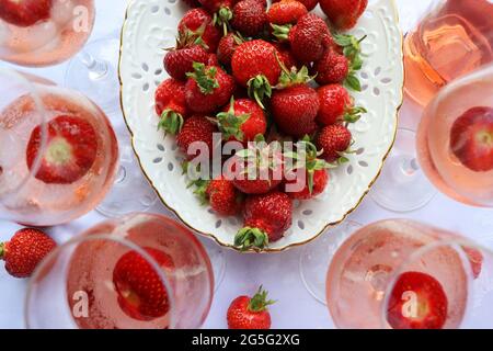 Kreative Komposition mit Rosenwein und leckeren Erdbeeren auf weißem Hintergrund, Draufsicht Stockfoto