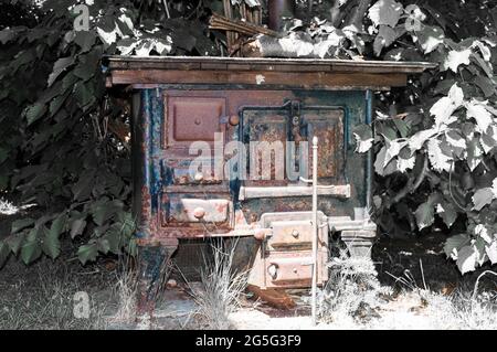 Alter Küchenofen, der mit Holz gefeuert wurde. Es ist dekorativ und im Garten bereits leicht rostend Stockfoto