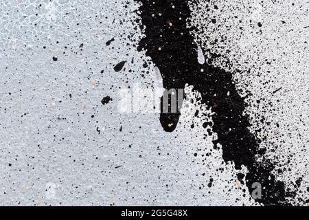 Makro-Nahaufnahme eines mit Weiß und Schwarz lackierten Wandsprays. Sprühen Sie Farbspritzer auf. Abstrakt Vollformat strukturiert spritzte Graffiti Hintergrund. Stockfoto