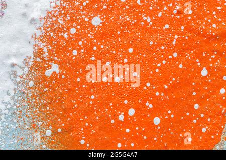 Makro-Nahaufnahme einer orangen Sprühfarbe mit weißen Spritzern. Abstrakter Vollformat strukturierter, spritzgetragener Graffiti-Hintergrund mit Platz für Kopien. Stockfoto