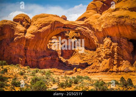 Riesige rote Bögen im Arches National Park in Utah, USA, mit Touristen, die wie Ameisen herumklettern. Stockfoto