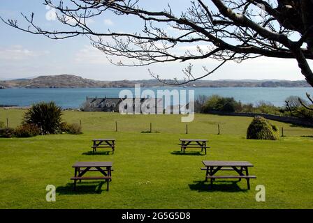 Vier unbesetzte Picknicktische in einer angenehmen Grünanlage mit Blick auf das Meer, Iona, Schottland Stockfoto