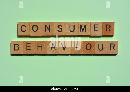Verbraucherverhalten, Wörter in Holzbuchstaben isoliert auf grünem Hintergrund Stockfoto