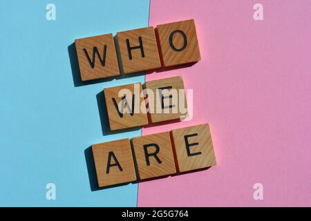 Wer wir sind, Wörter in hölzernen Buchstaben, isoliert auf blauem und rosa Hintergrund Stockfoto