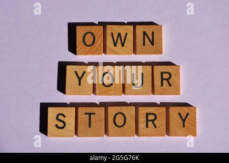 Eigene deine Geschichte, Wörter in hölzernen Alphabetischen Buchstaben isoliert auf purpurem Hintergrund Stockfoto