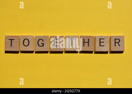 Zusammen, Wort in hölzernen Buchstaben Alphabet isoliert auf hellgelben Hintergrund Stockfoto