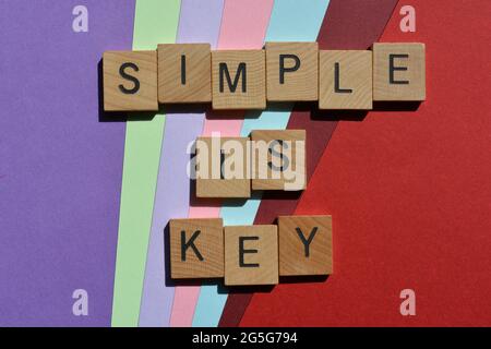 Einfach ist der Schlüssel, Wörter in hölzernen Buchstaben, isoliert auf buntem Hintergrund Stockfoto