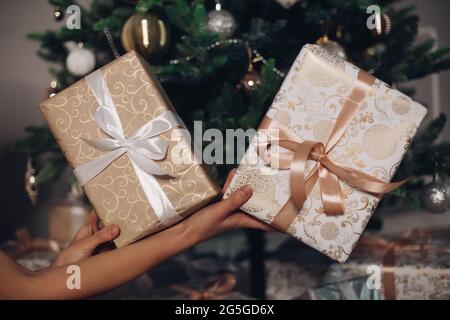 Zwei eingewickelte Weihnachtsgeschenke in Händen. Stockfoto