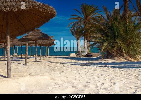 Blick auf den weißen Sandstrand und die Sonnenschirme an der Mittelmeerküste mit Birkenwasser. Stockfoto