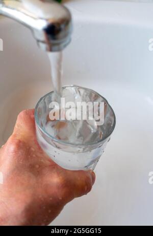 Ein Glas mit Leitungswasser füllen. Stockfoto