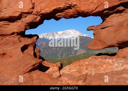 Blick auf den Pikes-Gipfel durch das Loch in der roten Felsformation der Siamesischen Zwillinge im Park Garden of the Gods in Colorado Springs, Colorado, USA Stockfoto