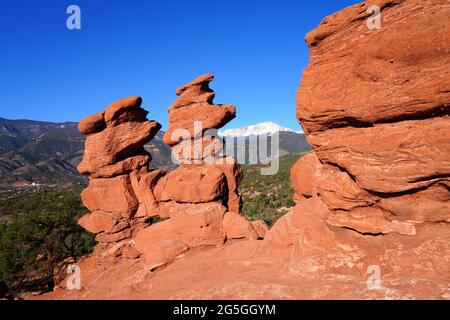 Blick auf den Pikes-Gipfel durch das Loch in der roten Felsformation der Siamesischen Zwillinge im Park Garden of the Gods in Colorado Springs, Colorado, USA Stockfoto