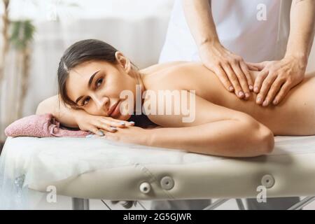 Eine junge, schöne Frau befindet sich im Salon am Empfang eines Masseurs und ruht sich während einer Therapiesitzung aus. Stockfoto
