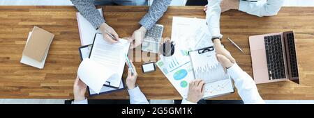 Geschäftsleute an ihrem Schreibtisch unterschreiben Vertrag und schütteln sich gegenseitig Stockfoto