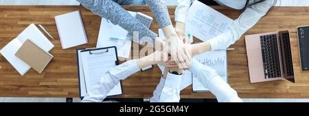 Geschäftsleute und Geschäftsfrau am Arbeitstisch halten ihre Hände zusammen Stockfoto