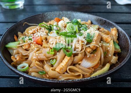 Gebratene Nudeln mit geschreddertem Huhn und Frühlingszwiebeln in der Pfanne Stockfoto