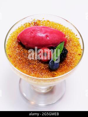 Karamellisierte Vanillecreme Brulee mit Himbeer-Sorbet und Beeren mischen Stockfoto