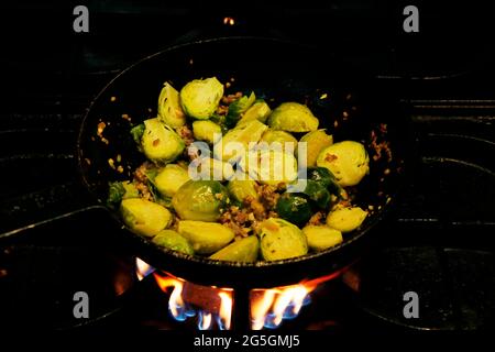 brüsseler Sprossen und Rinderspeck kochen in einer Pfanne auf Feuer Stockfoto