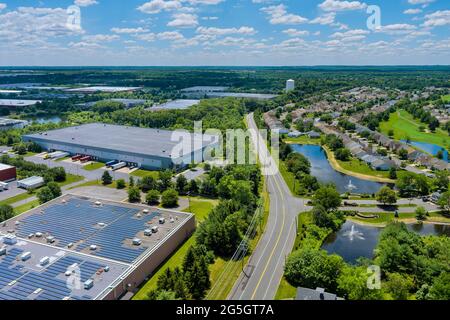 Luftpanorama auf Sonnenkollektoren auf absorbieren Sonnenlicht nachhaltige Energie des Gebäudes Lagerhaus Dach in der Nähe einer kleinen amerikanischen Stadt Stockfoto