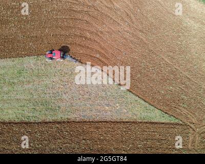 Eine Luftaufnahme eines Traktors, der durch ein Feld pflügt Stockfoto