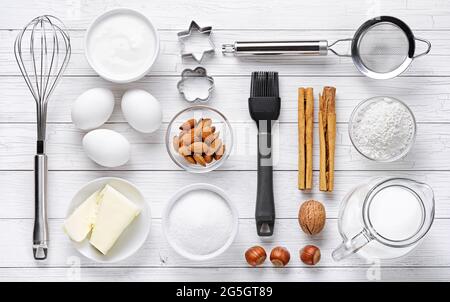 Backwerkzeuge und Zutaten, die für die Zubereitung von Desserts benötigt werden. Draufsicht auf weißem Holzhintergrund. Stockfoto